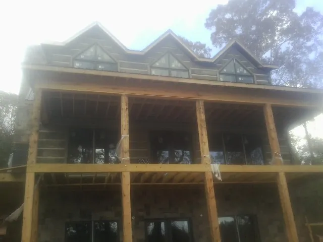 Dormers and porch framing on a large log home under construction — Roof Coating work by our crew in Limon