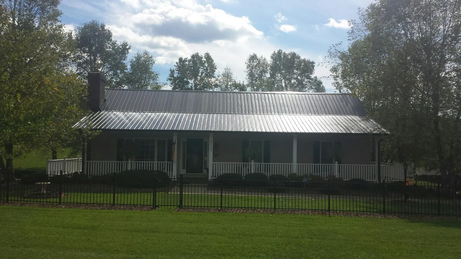 Gray metal roof on a brick ranch with a full width front porch — Gutter Guard Installation work by our crew in Limon