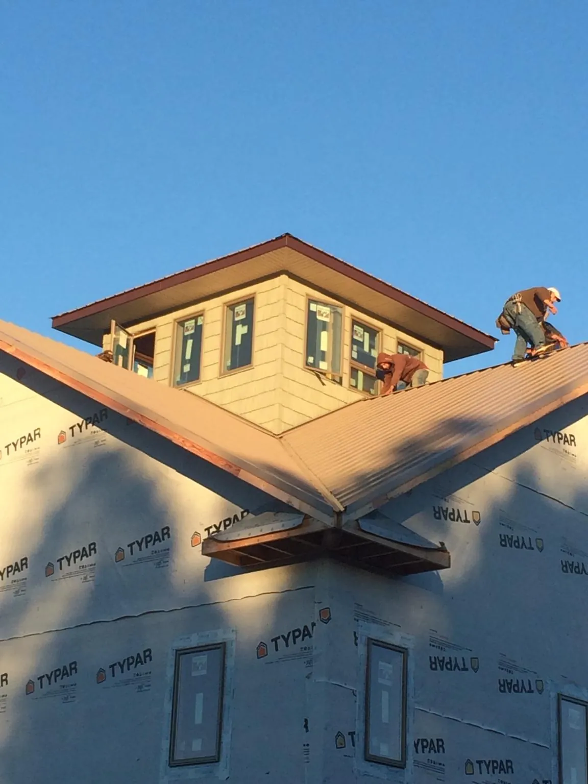 Roofers working around a rooftop cupola on a new metal roof at sunset — Roof Waterproofing in Limon by Roofing Brothers